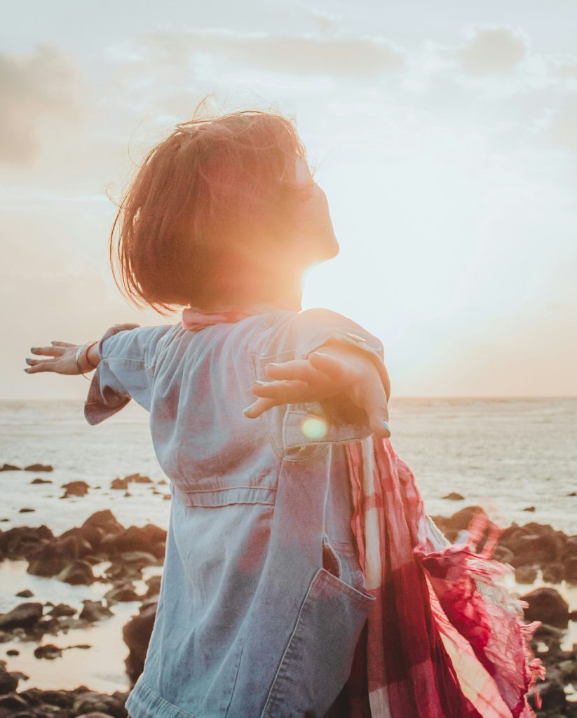 woman with arms open wide by the seaside